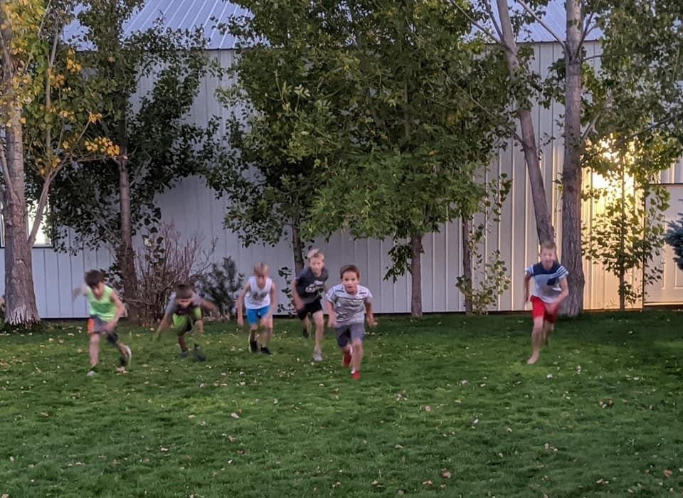 Boys running a sprint race across a grassy yard at dusk.