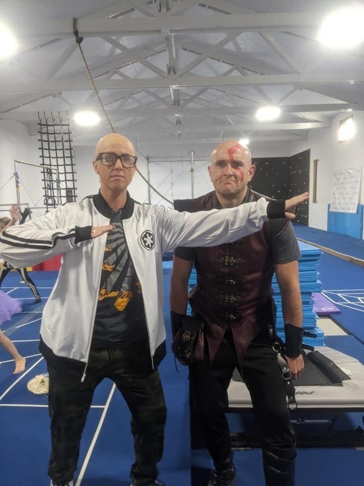 Two adults in Star Wars costumes posing in the gym during a themed event.
