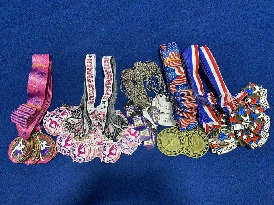 An assortment of gymnastics and parkour medals laid out on a blue mat.